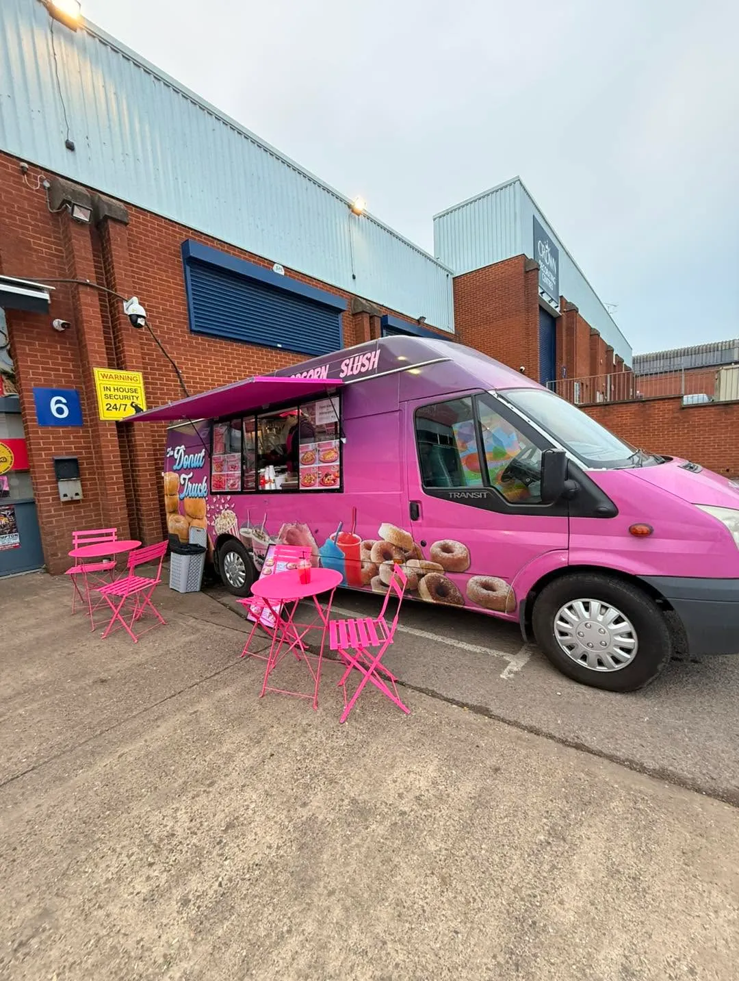 The pink Royal Pink van with the hatch open and cafe tables set up outside